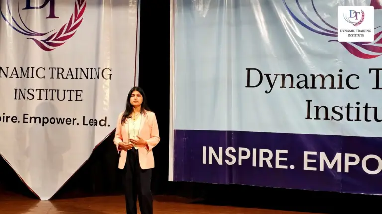 A participant standing on stage at Dynamic Training Institute, ready to speak