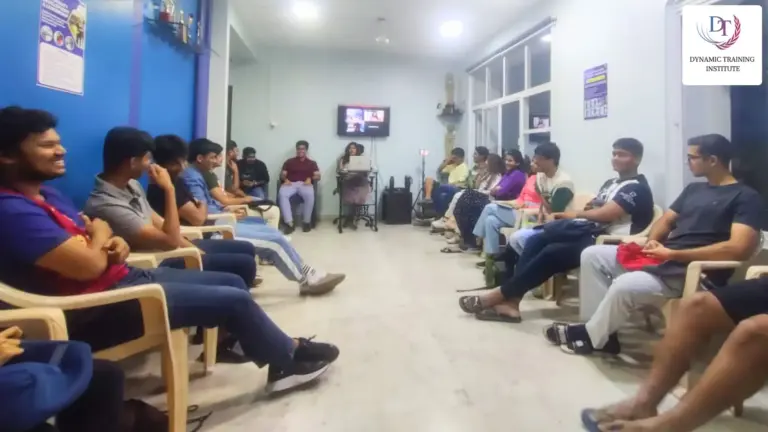 Young people seated in a circle in a training room, listening to a session