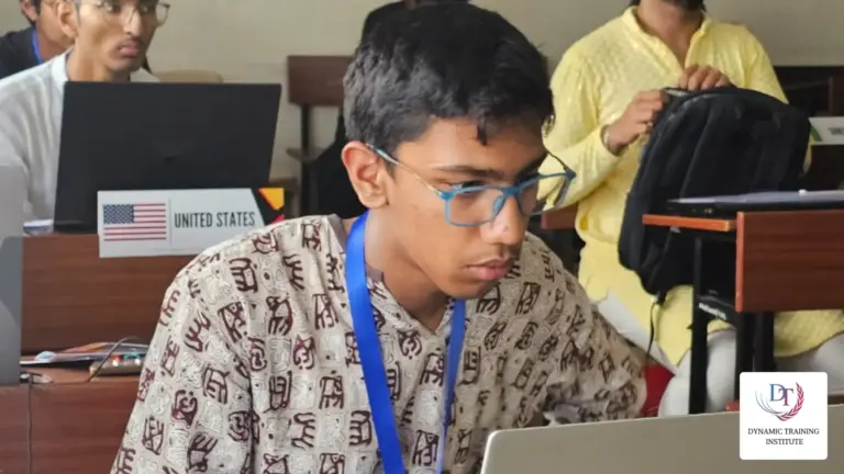 A young participant wearing a lanyard works on a laptop at a desk with a “United States” country placard