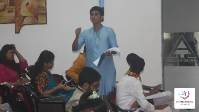 A young man in a kurta speaking to a seated group in a classroom