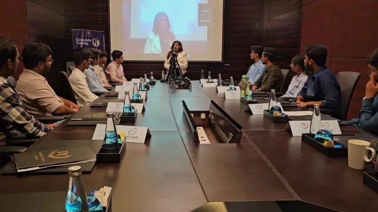 A trainer speaking to professionals around a boardroom table, also shown on the screen, at Glide Cloud