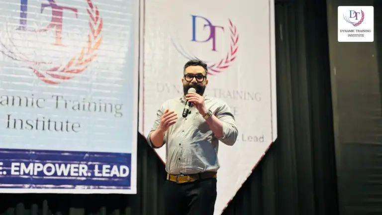 A speaker with a microphone on the stage at Dynamic Training Institute