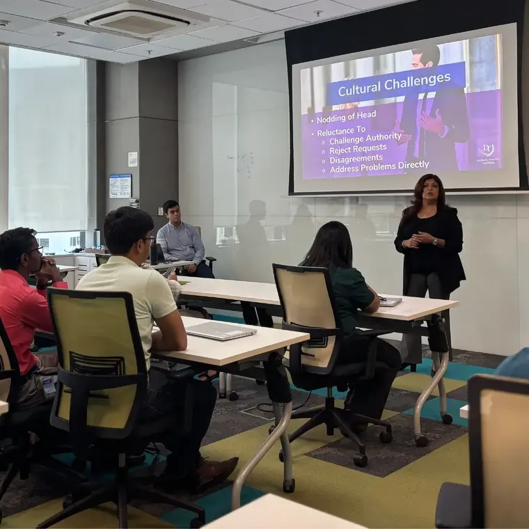 Tina Shah teaching a corporate workshop on cultural challenges, participants seated at desks