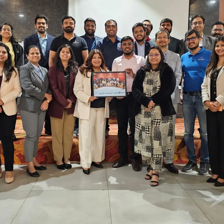 Group photo of a corporate training batch standing together, two of them holding up a framed certificate