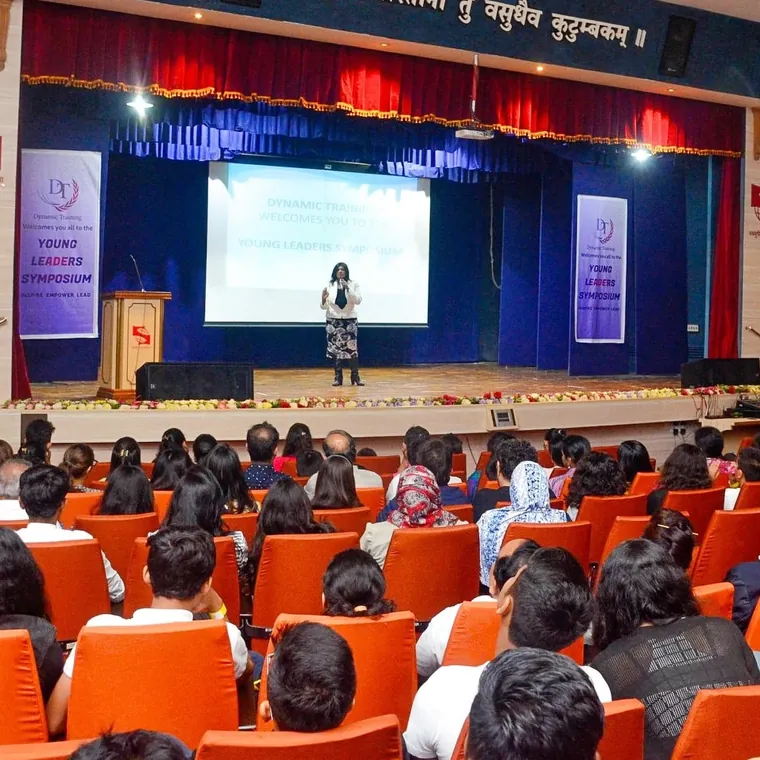 A full auditorium of students listening to a speaker on stage at a leadership symposium