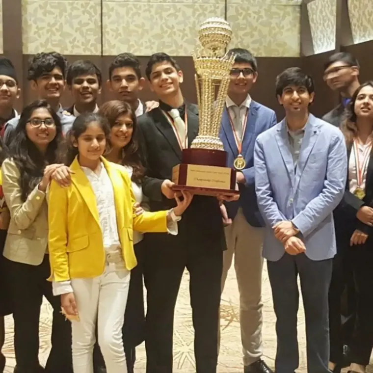 Students in formal clothes celebrating with a trophy and medals