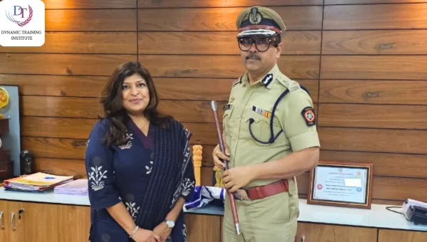 A woman standing beside a senior police officer in uniform holding a ceremonial baton