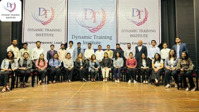 Group photo of a training batch in front of Dynamic Training Institute banners reading “Inspire. Empower. Lead.”