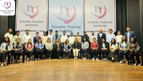 Group photo of a training batch in front of Dynamic Training Institute banners reading “Inspire. Empower. Lead.”