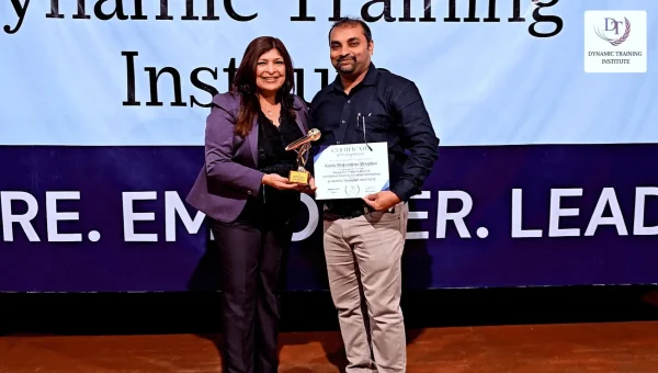 Tina Shah hands a certificate and a trophy to a graduate on stage at Dynamic Training Institute