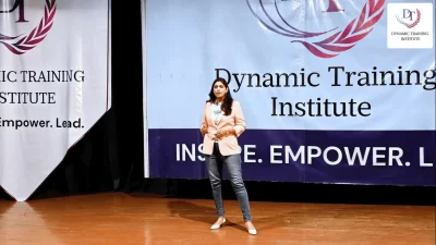 A woman speaking on stage in front of the Dynamic Training Institute banner