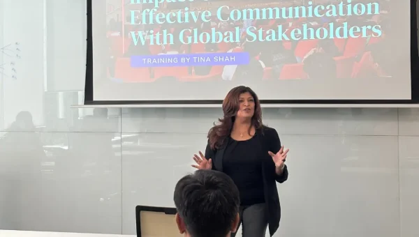 A woman trainer presenting in front of a projected slide titled “Impact Of Culture On Effective Communication With Global Stakeholders”