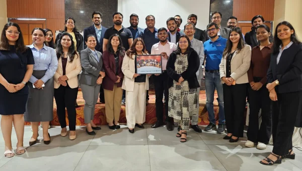 Group photo of a corporate training batch standing together, two of them holding up a framed certificate