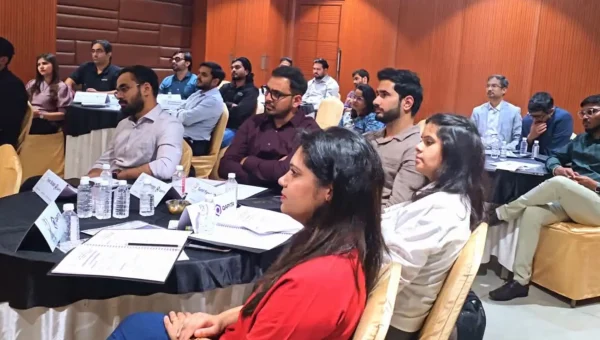Professionals seated at round tables listening during a corporate training session in a hotel room