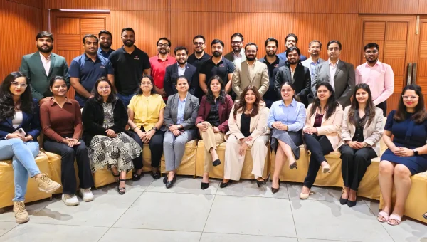 Group photo of a corporate training batch, the front row seated on a sofa and the back row standing behind