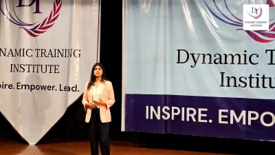 A participant standing on stage at Dynamic Training Institute, ready to speak