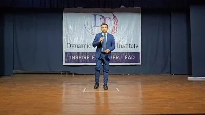 A participant in a suit speaking from the stage of an auditorium at Dynamic Training Institute